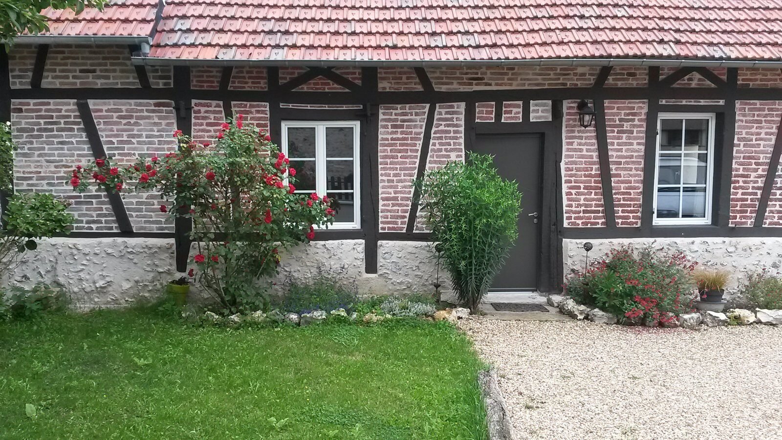 Façade normande fleurie du gîte Le Romarande
