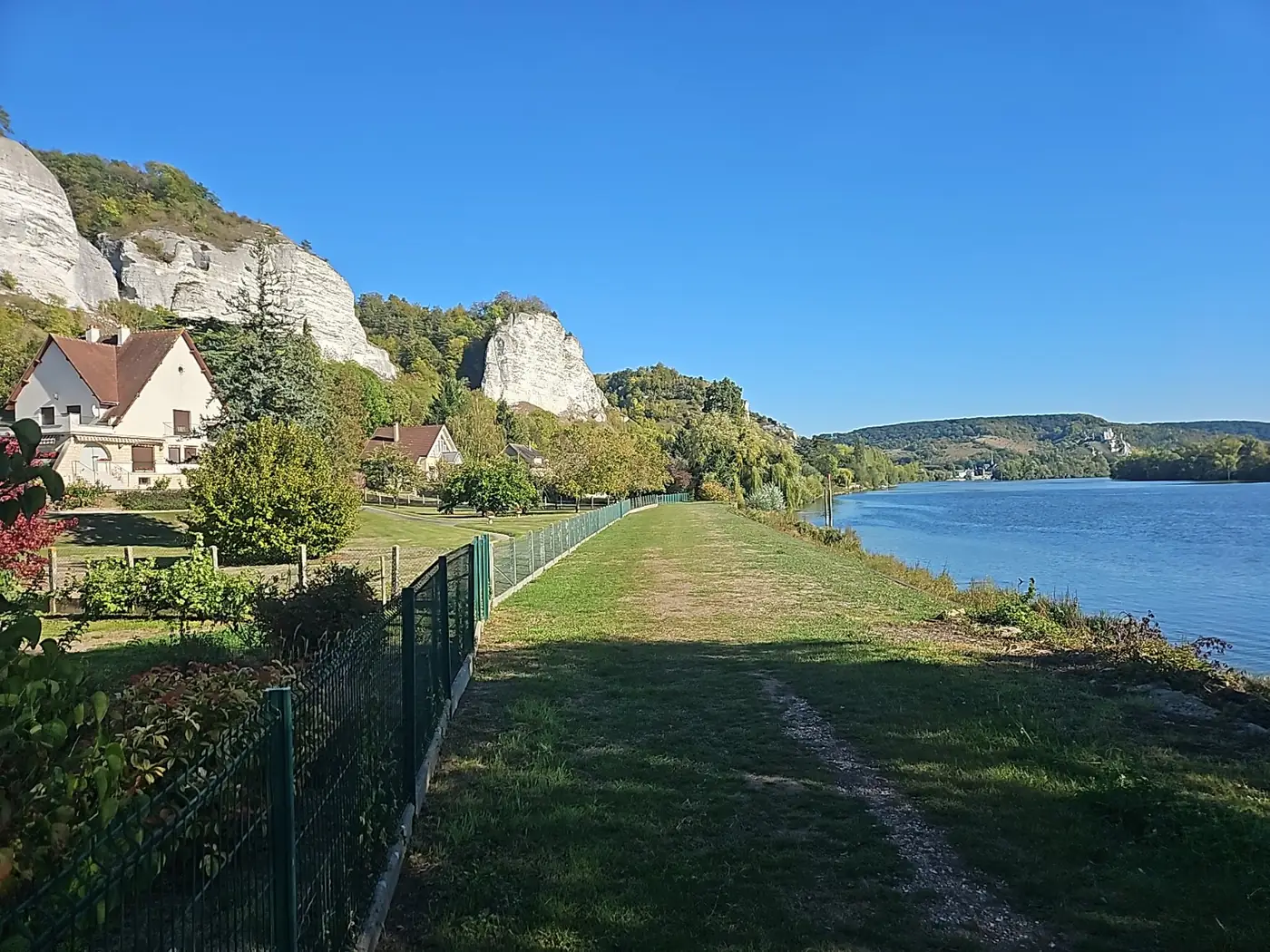 Chemin herbeux au bord de la Seine avec les falaises des Andelys